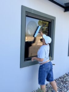 Cleaning business operator demonstrating hands-on window cleaning technique